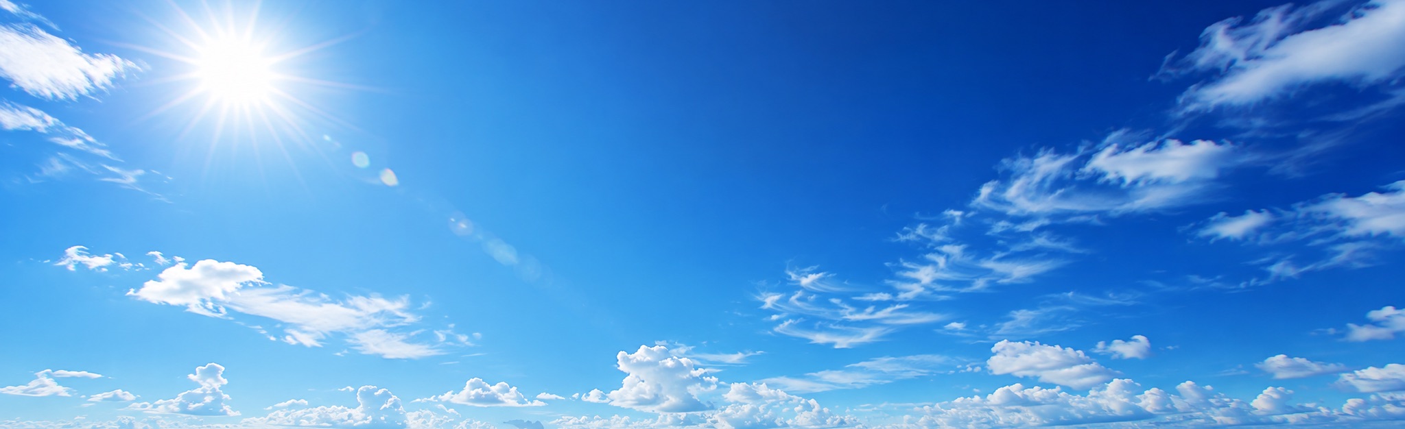 強い日差しの下に青空と白い雲が広がる風景